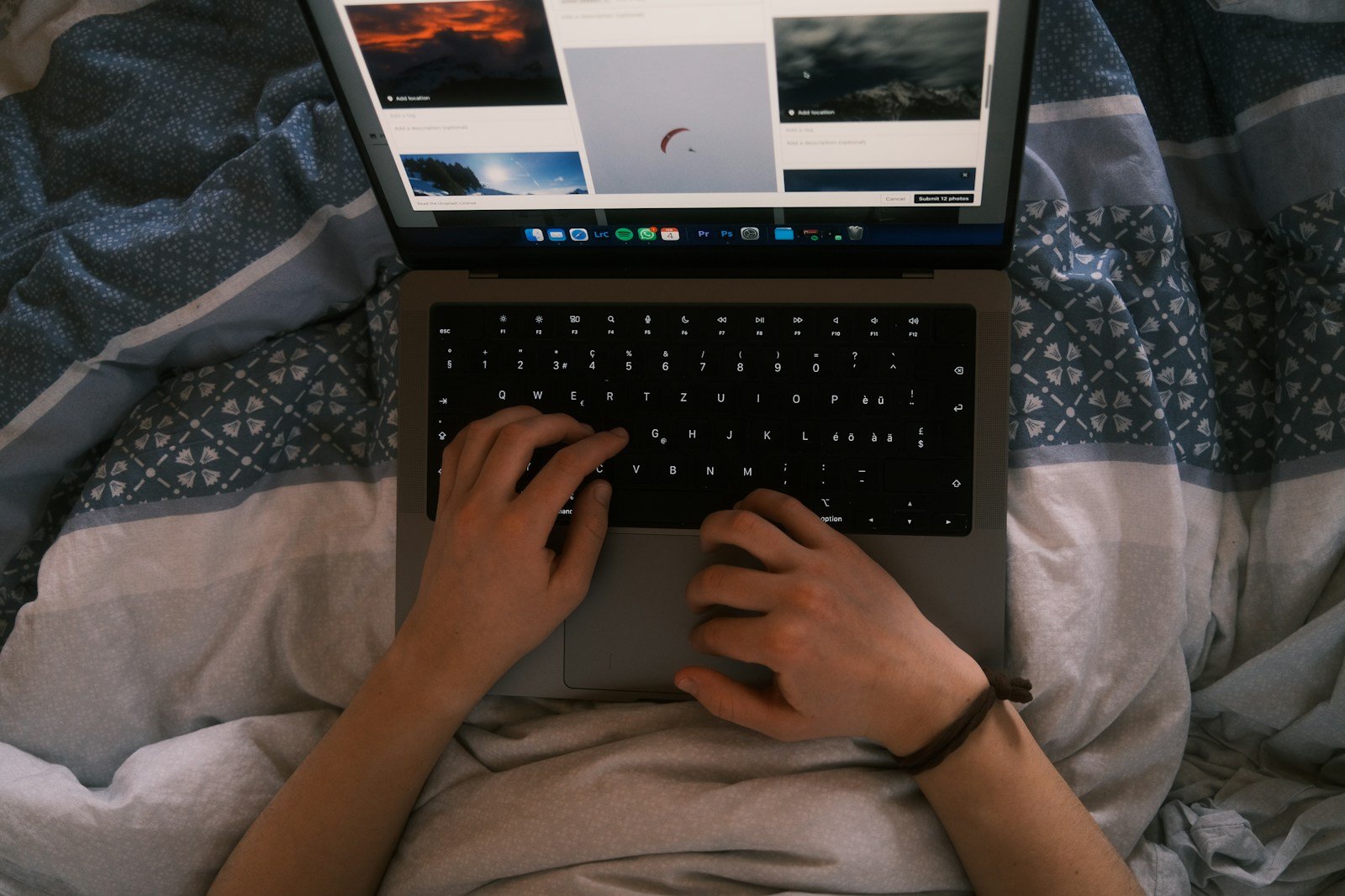 a person typing on a laptop on a bed
