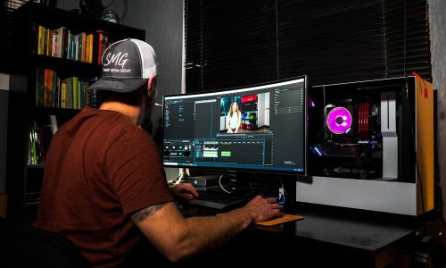 man in red t-shirt sitting in front of computer