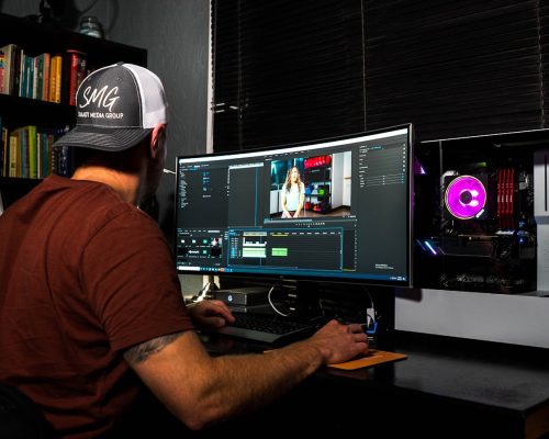 man in red t-shirt sitting in front of computer